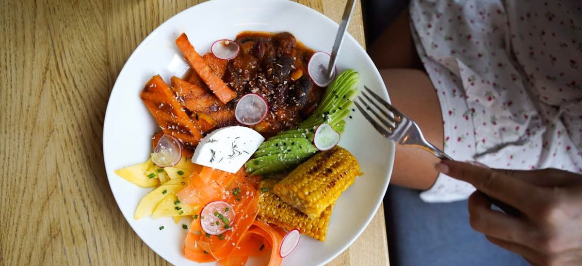 Colorful vegetarian meal with avocado, beans, and corn served on a wooden table. Ideal for healthy lifestyle visuals.